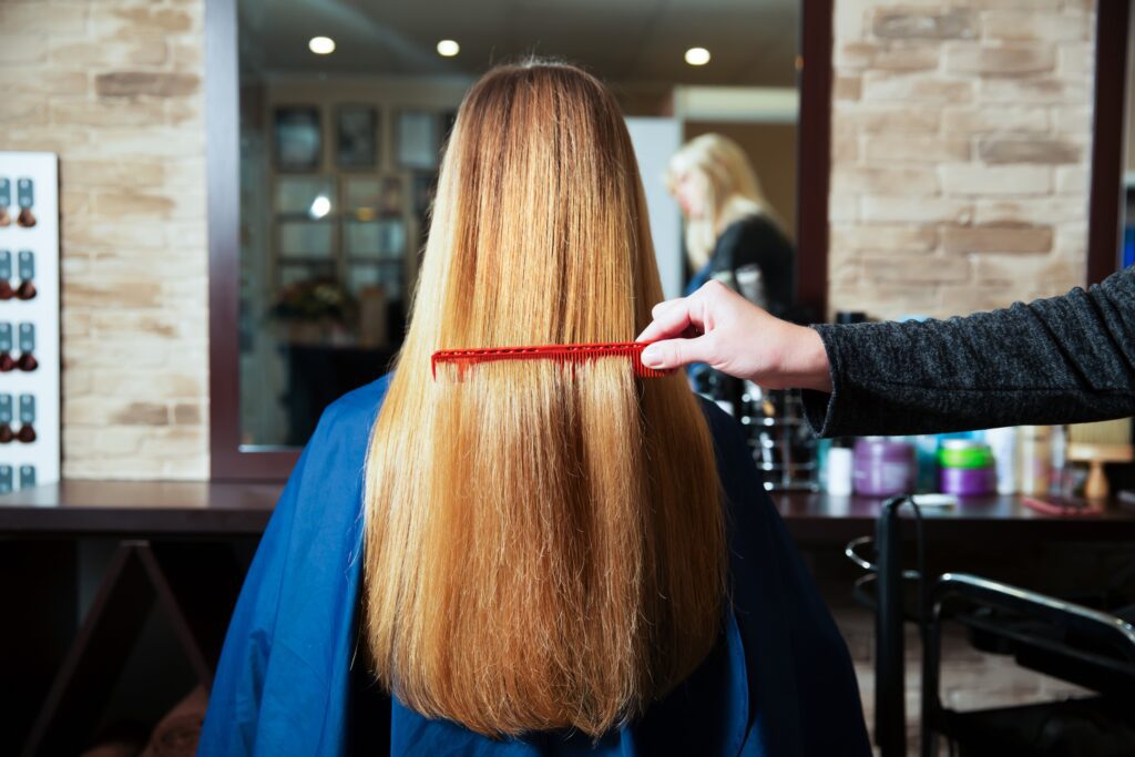 Someone is gently combing the hair of a young girl with a bright red comb